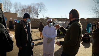 een groep hulpverleners praten met elkaar buiten een kliniek in Kandahar, Afghanistan