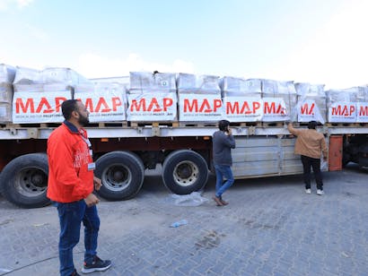 hulpverlener met oranje jas van medical aid for palestinians staat voor hulpkonvooi in Egypte