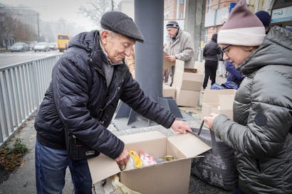 Een oudere man deelt voedsel uit in Oekraïne aan mensen in nood
