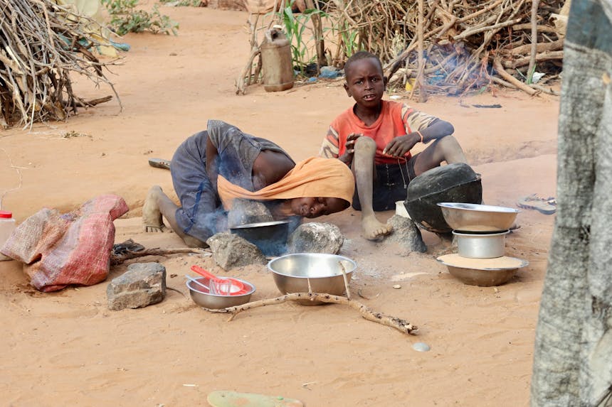 Een meisje probeert vuur te maken om voor haar familie te kunnen koken in een Soedanees vluchtelingenkamp.