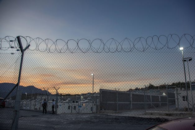vluchtelingenkamp op samos achter prikkeldraad tijdens zonsondergang