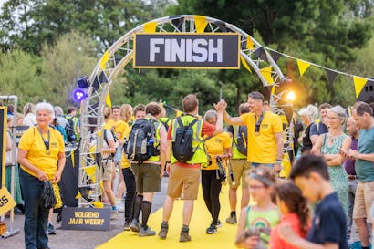 mensen staan in gele shirts bij de finish van de jaarlijkse sponsorloop Nacht van de Vluchteling