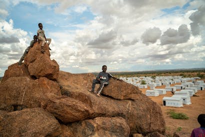 Drie jongetjes zitten voor een vluchtelingenkamp in Tsjaad