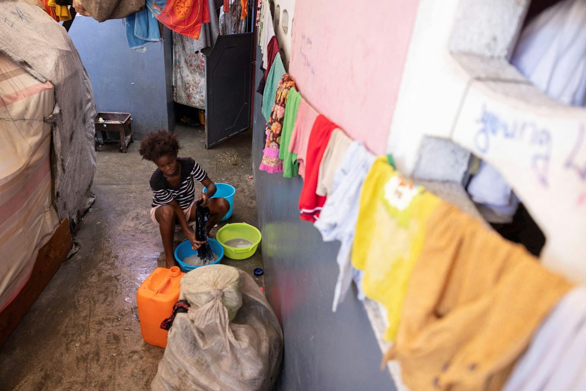 Een meisje wast haar kleiding in een opvang voor ontheemden