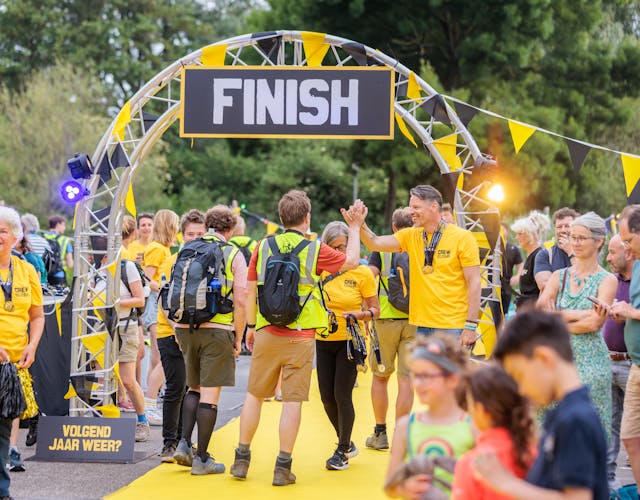 mensen staan in gele shirts bij de finish van de jaarlijkse sponsorloop Nacht van de Vluchteling