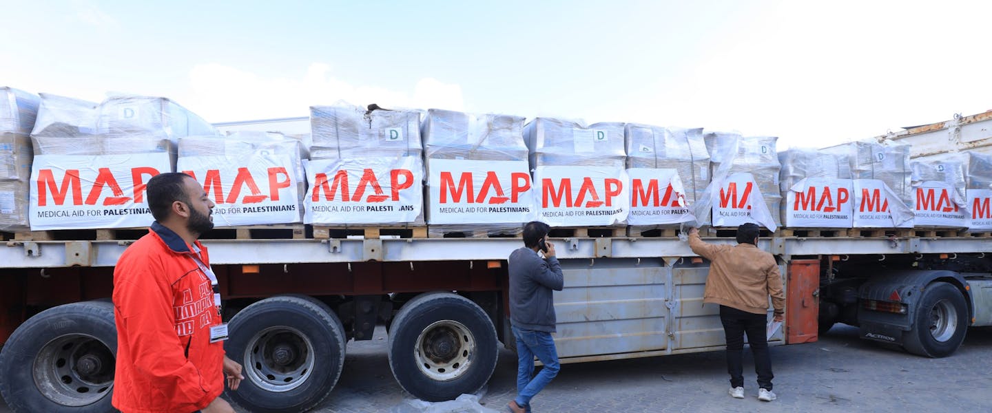 hulpverlener met oranje jas van medical aid for palestinians staat voor hulpkonvooi in Egypte