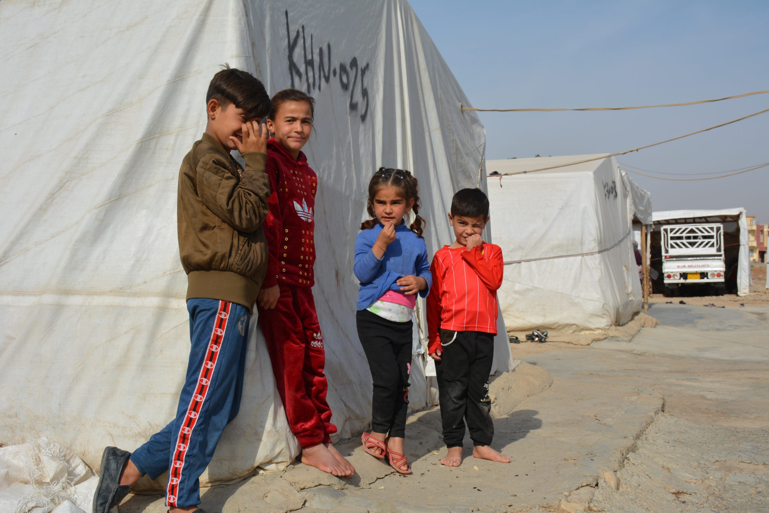 kinderen op de vlucht in libanon staan voor een witte tent in een opvangkamp