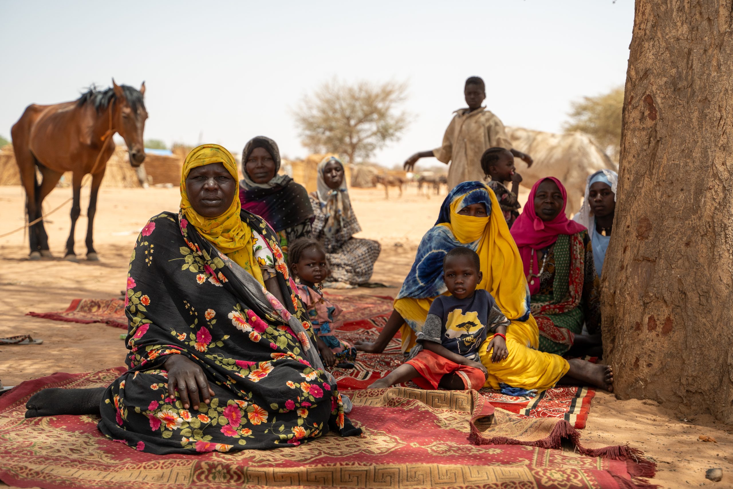 groep vluchtelingen zit op kleedje in tsjaad