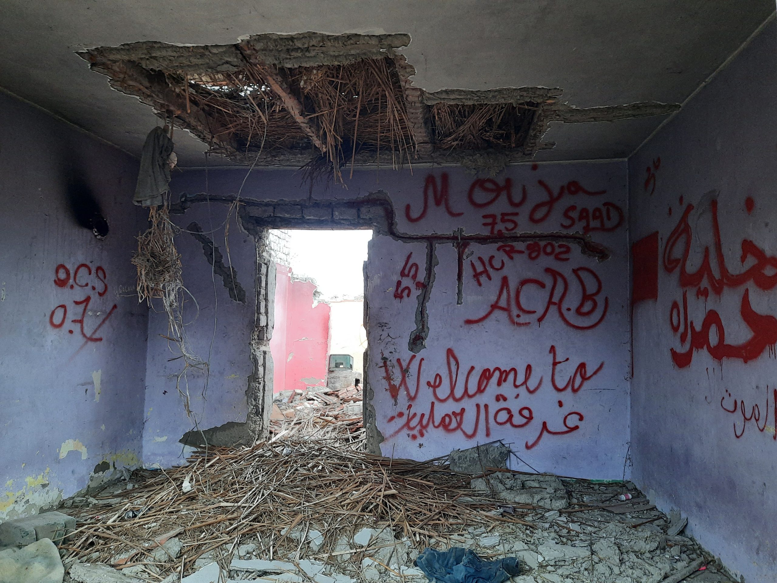 verlaten gebouw waar vluchtelingen schuilen, op de blauwe, afgebladderde muren staan teksen