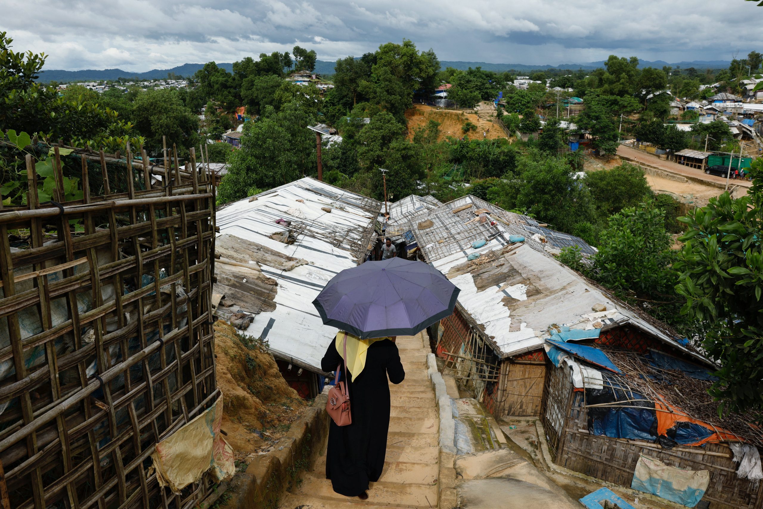 Een Rohingya-vluchteling loopt met paraplu boven haar hoofd door Cox's Bazar in Bangladesh