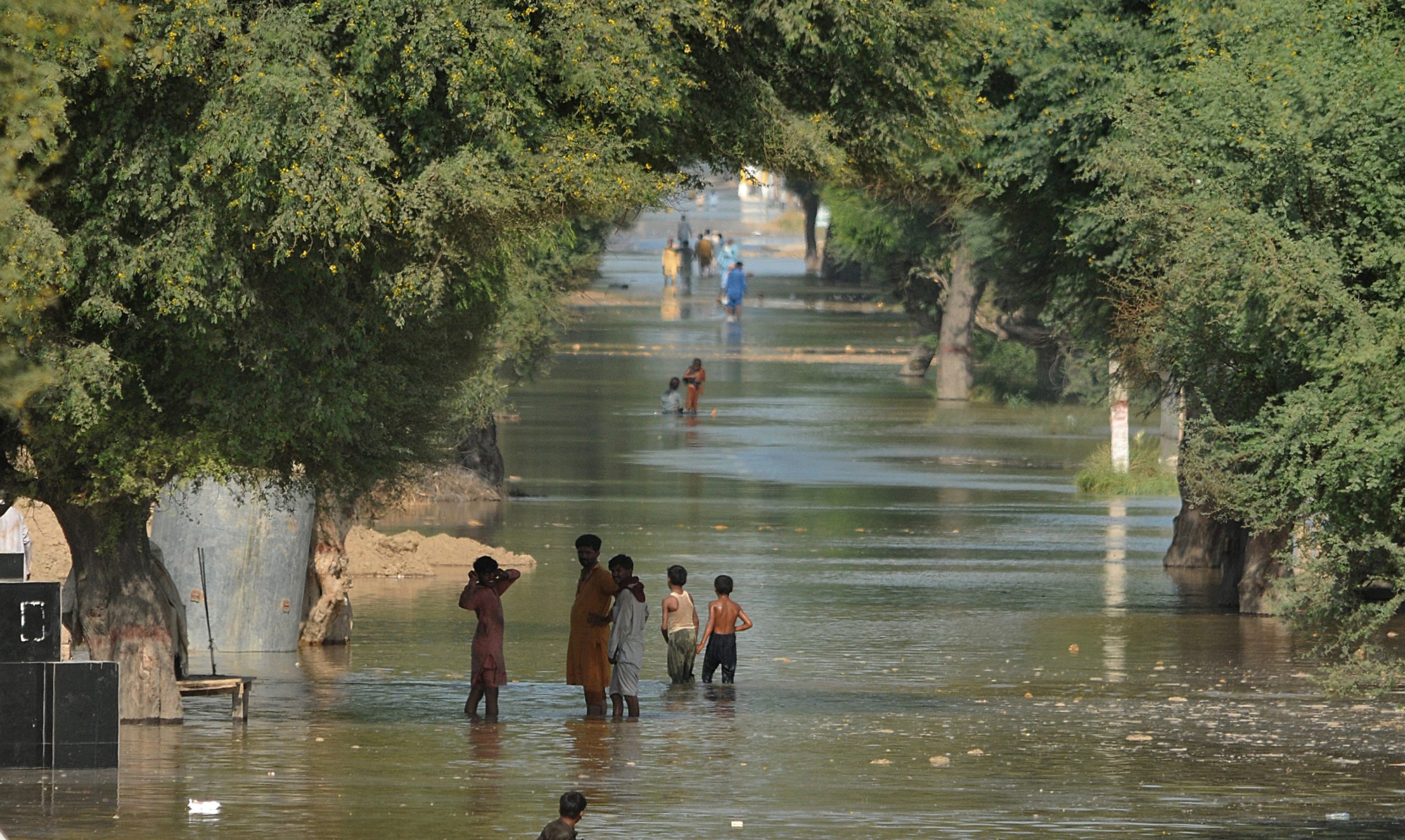 Pakistaanse slachtoffers van overstromingen lopen over een overstroomde straat na overstromingen in hun leefomgeving