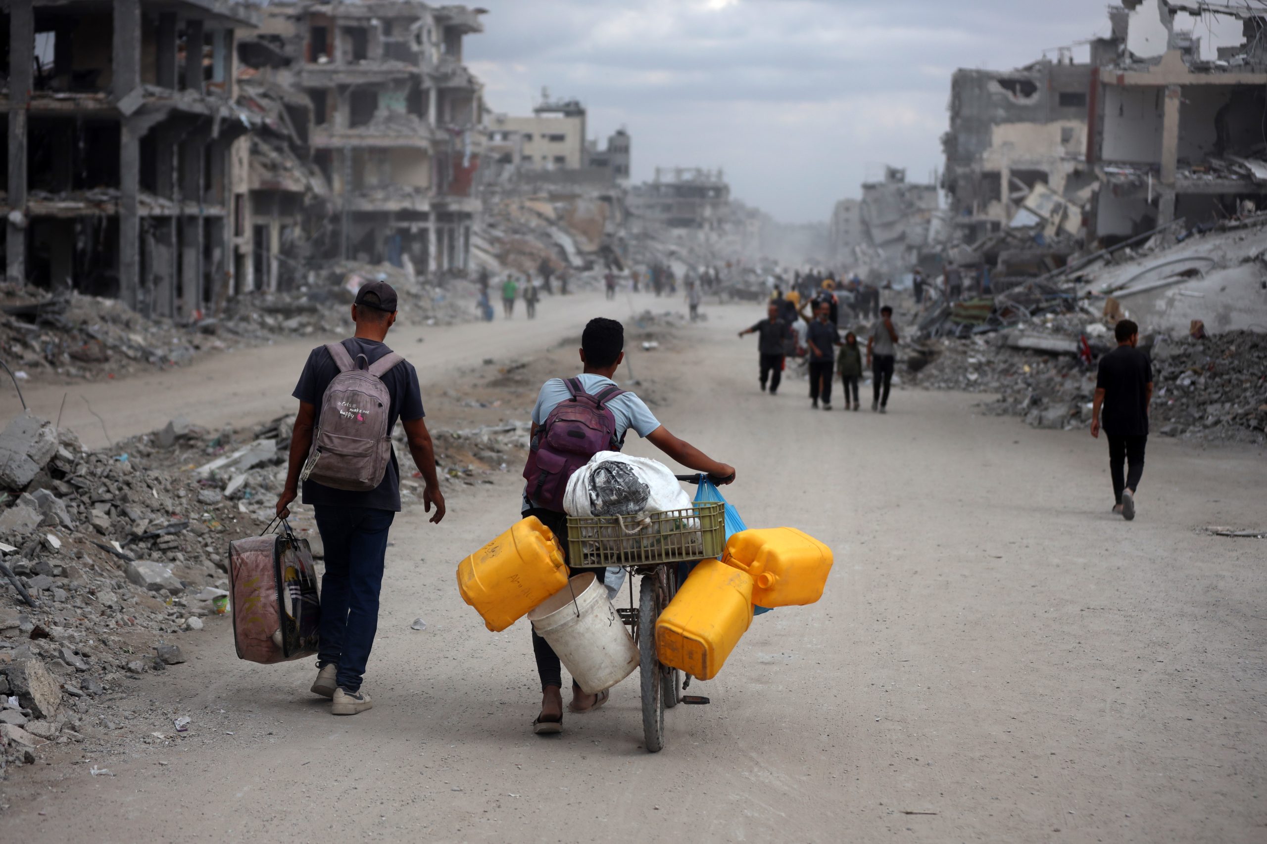 Twee Palestijnen keren terug naar Gaza met jerrycans en een tas met bezittingen na de aankondiging van het staakt-het-vuren