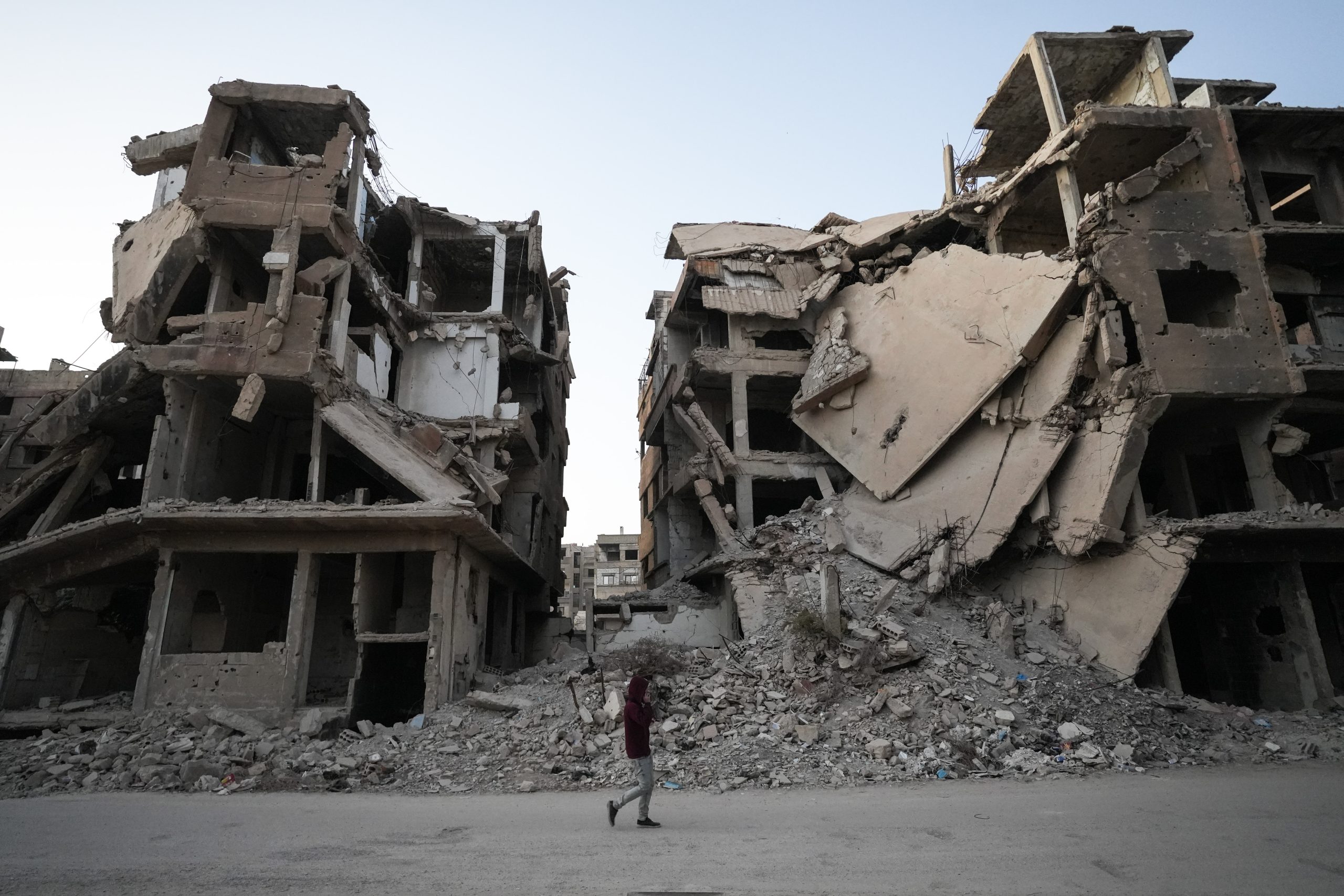 Een Syrische jongen loopt voor een verwoest gebouw langs in Harasta, Syrie.