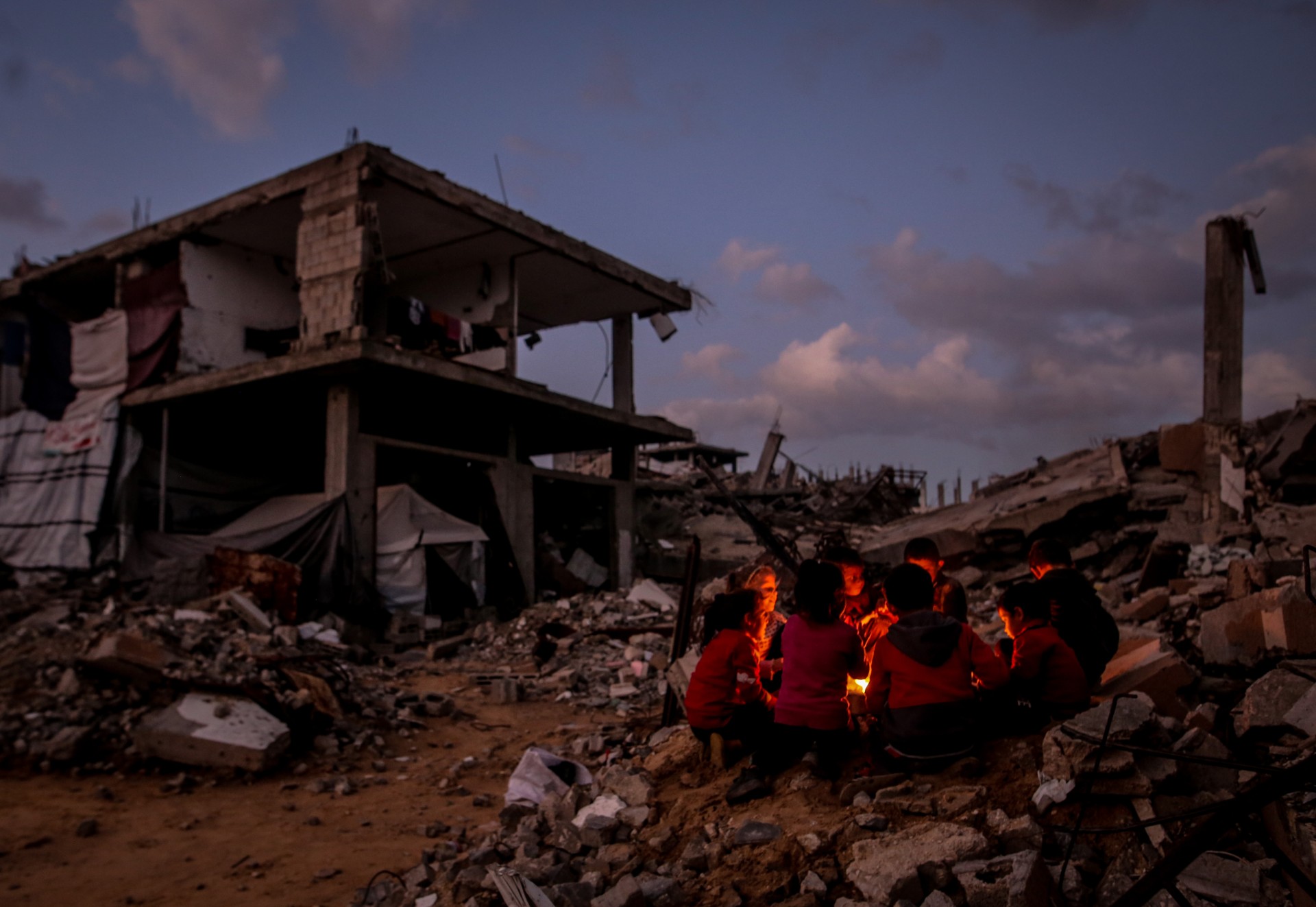 in Gaza maken ontheemde Palestijnen een vuur tussen het puin om op te warmen