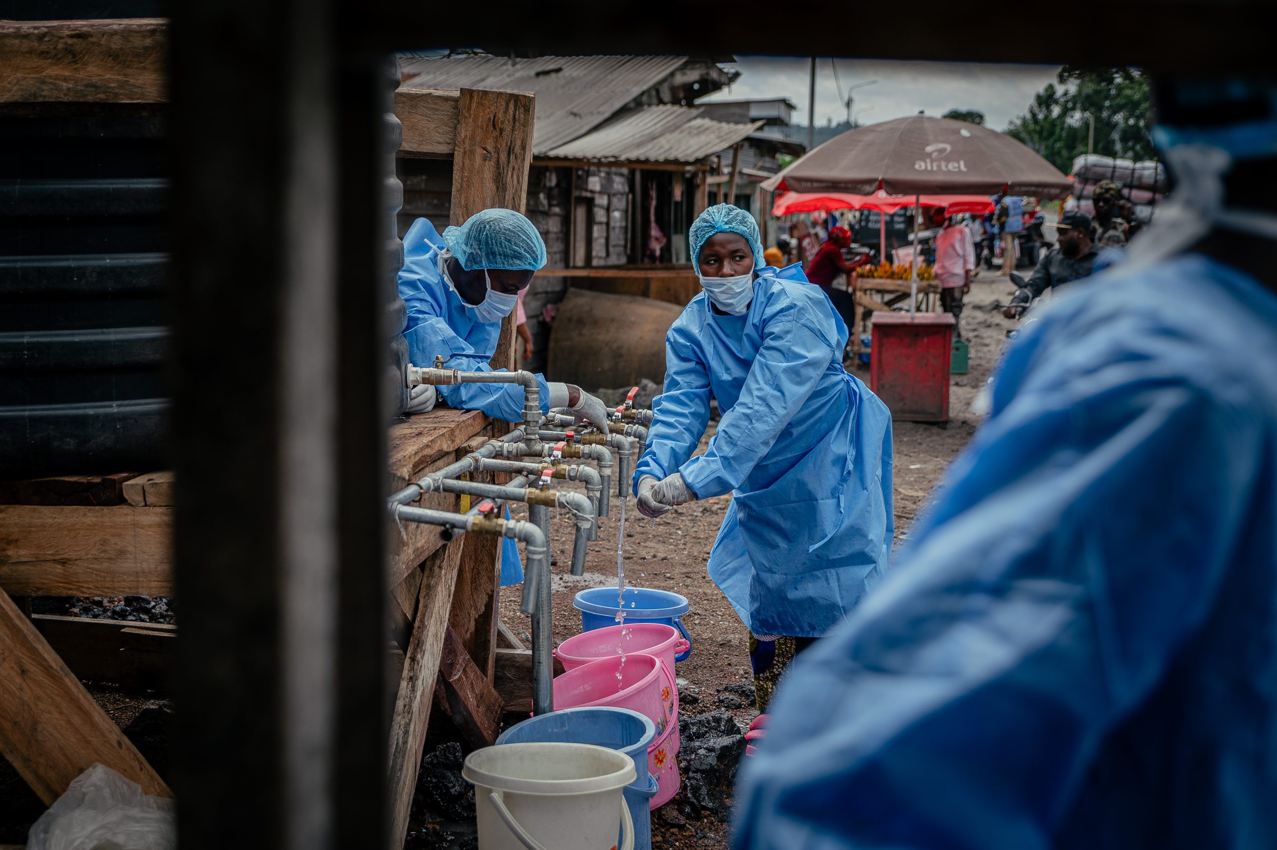 Hulpverleners bij een waterpunt in Goma, DR Congo, waar mensen hun handen kunnen wassen
