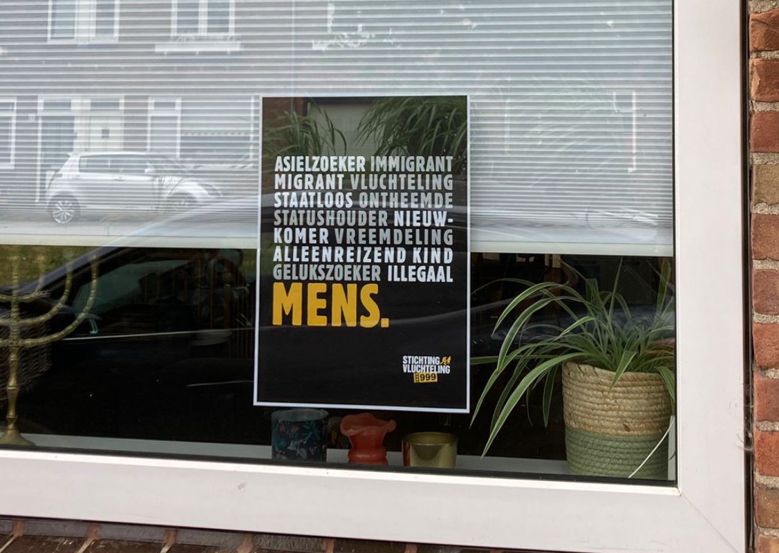 De Mens-poster hangt in een raam