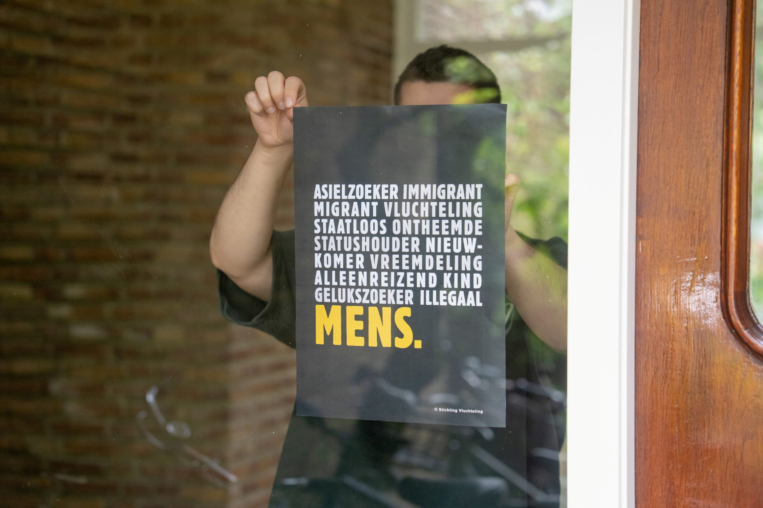 De Mens-poster hangt in een raam