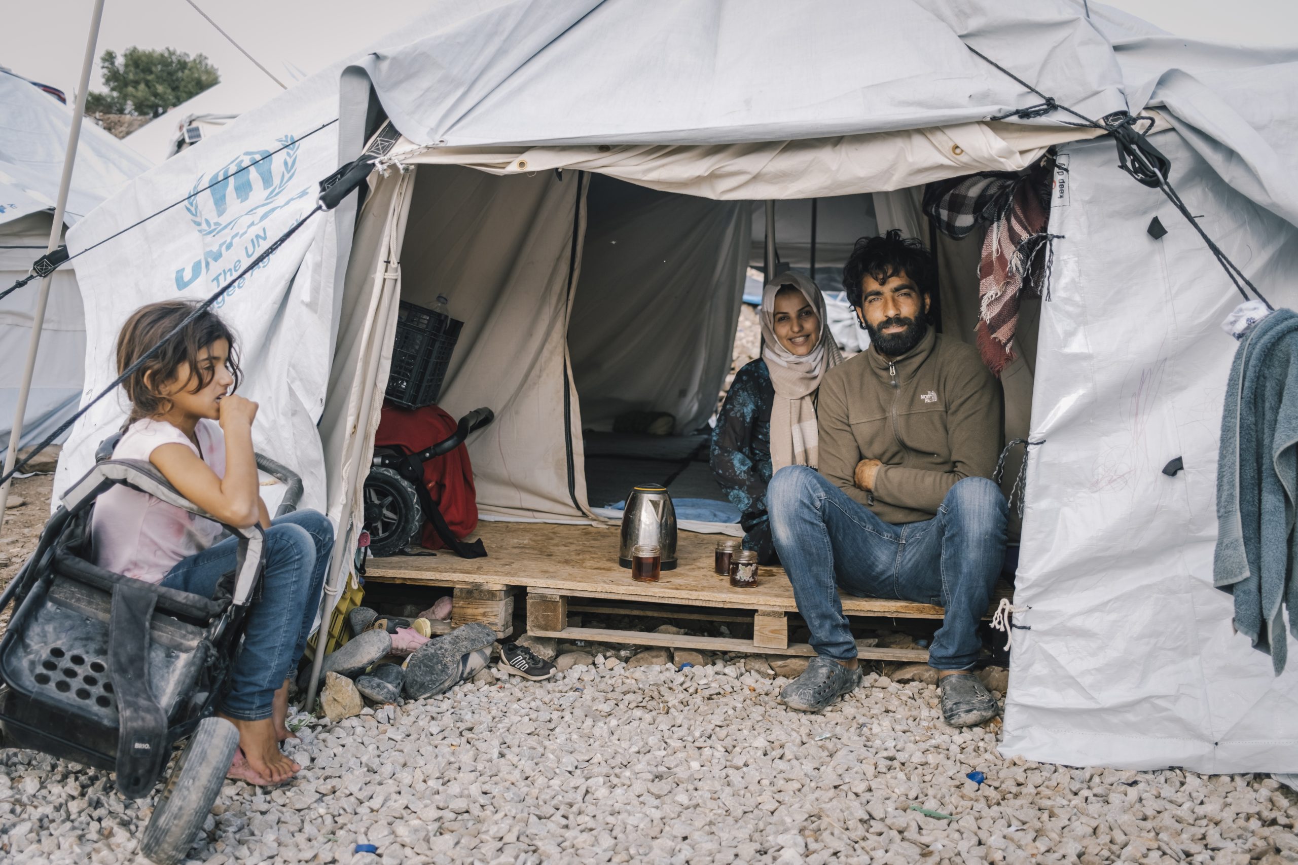 man en twee kinderen zitten in tent bij vluchtelingenkamp op Lesbos