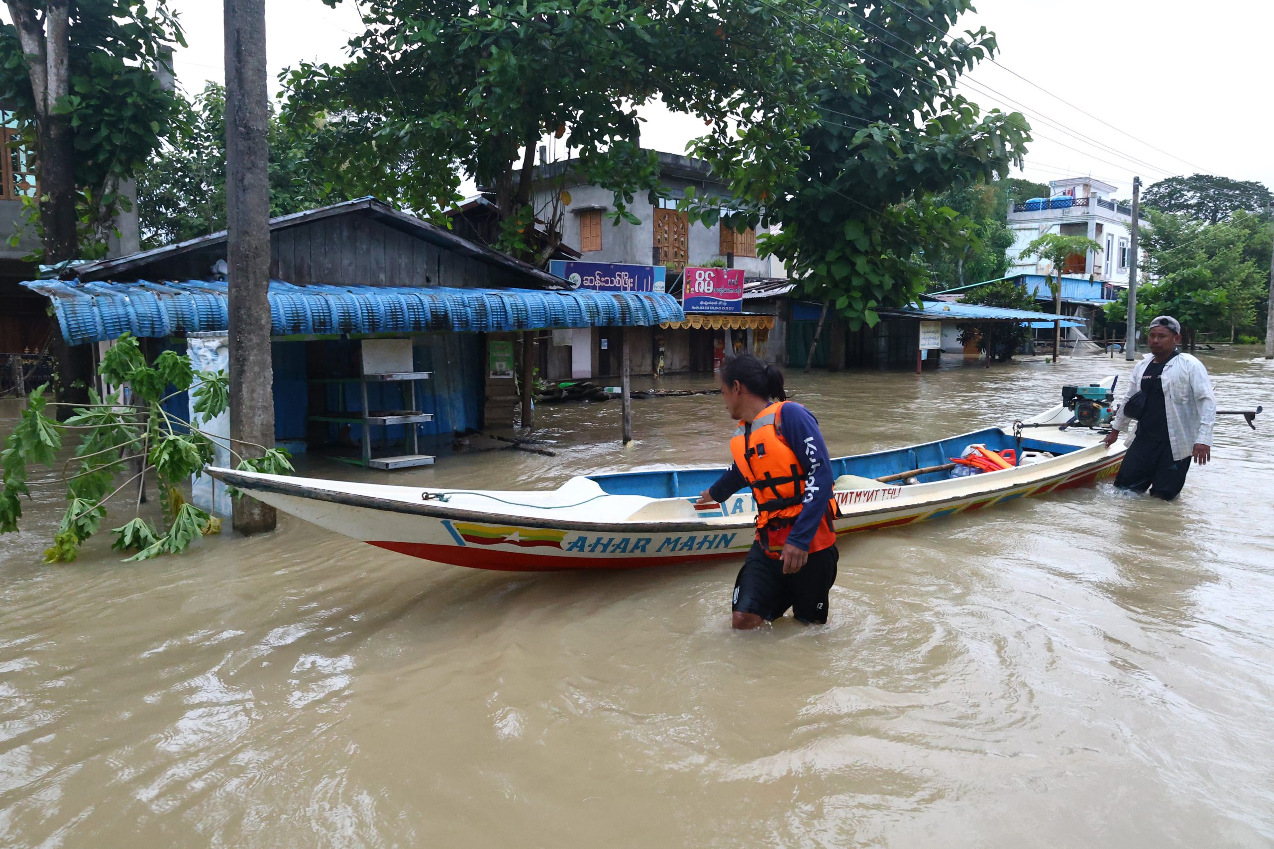 mensen stappen in een boot op een overstroomde straat in Myanmar